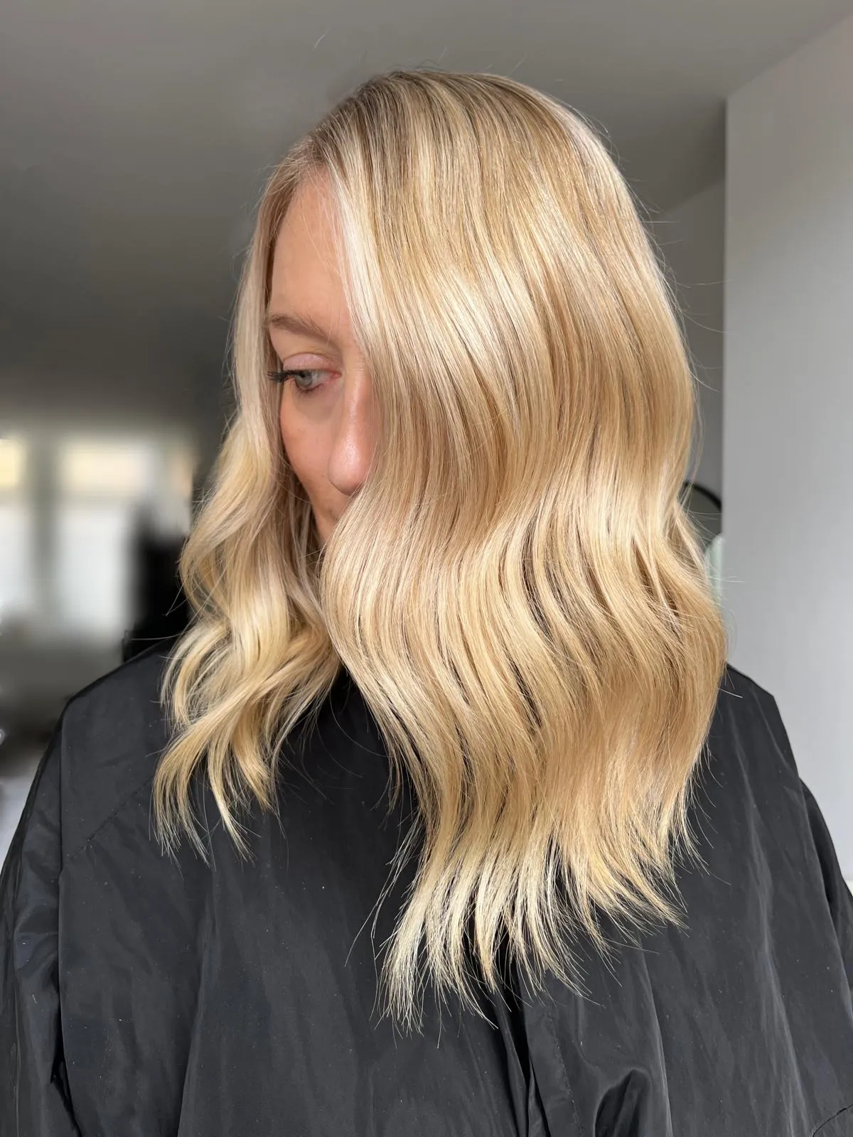 Side view after: bright golden blonde with polished soft waves and an even tone.