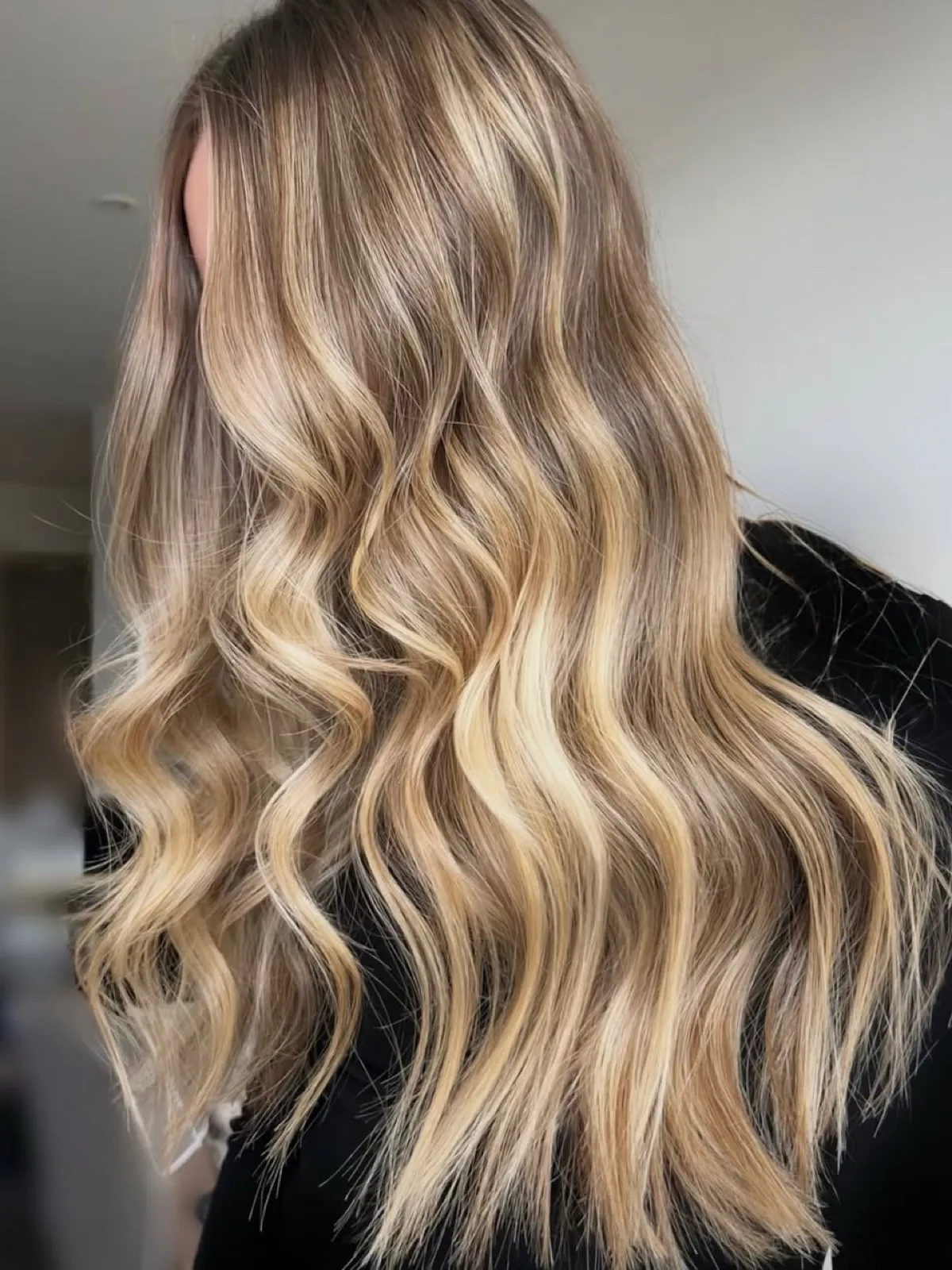 Side view after: bright dimensional blonde balayage with deep waves through the lengths.
