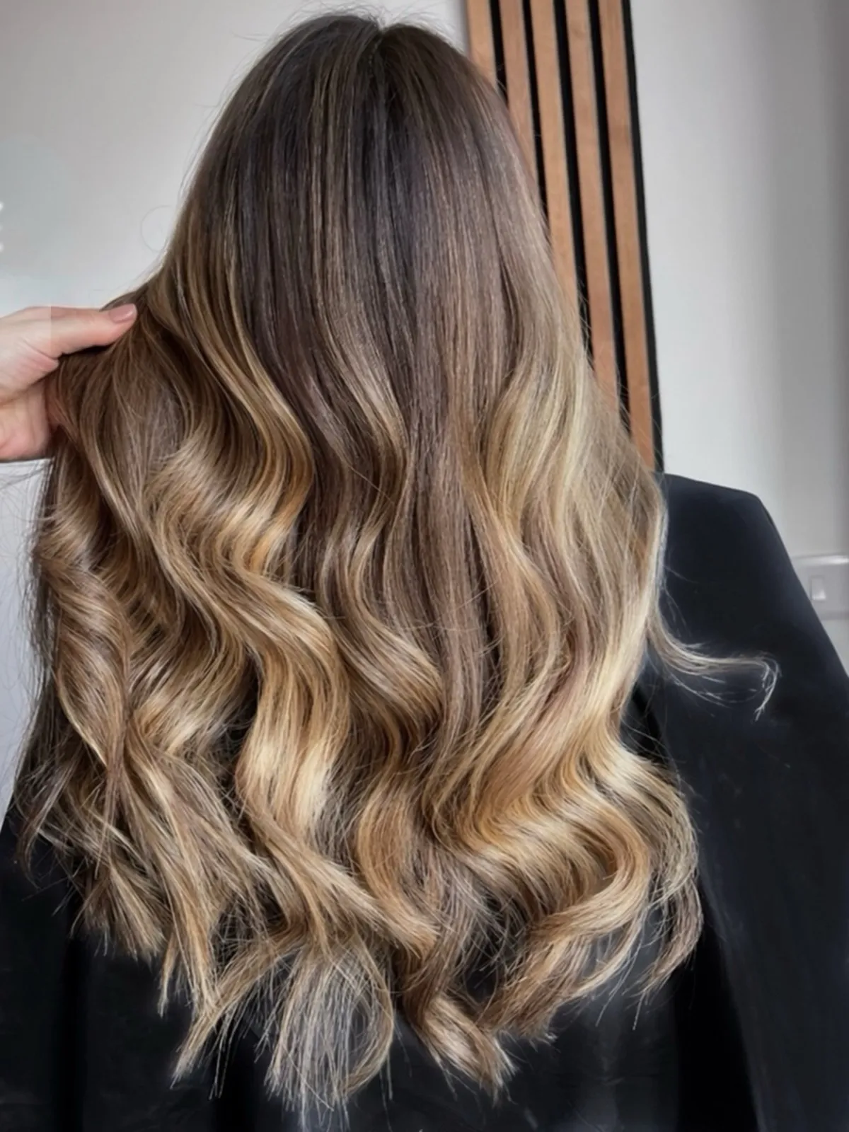 Rear view after: warm bronde balayage with caramel through the lengths and glossy waves.