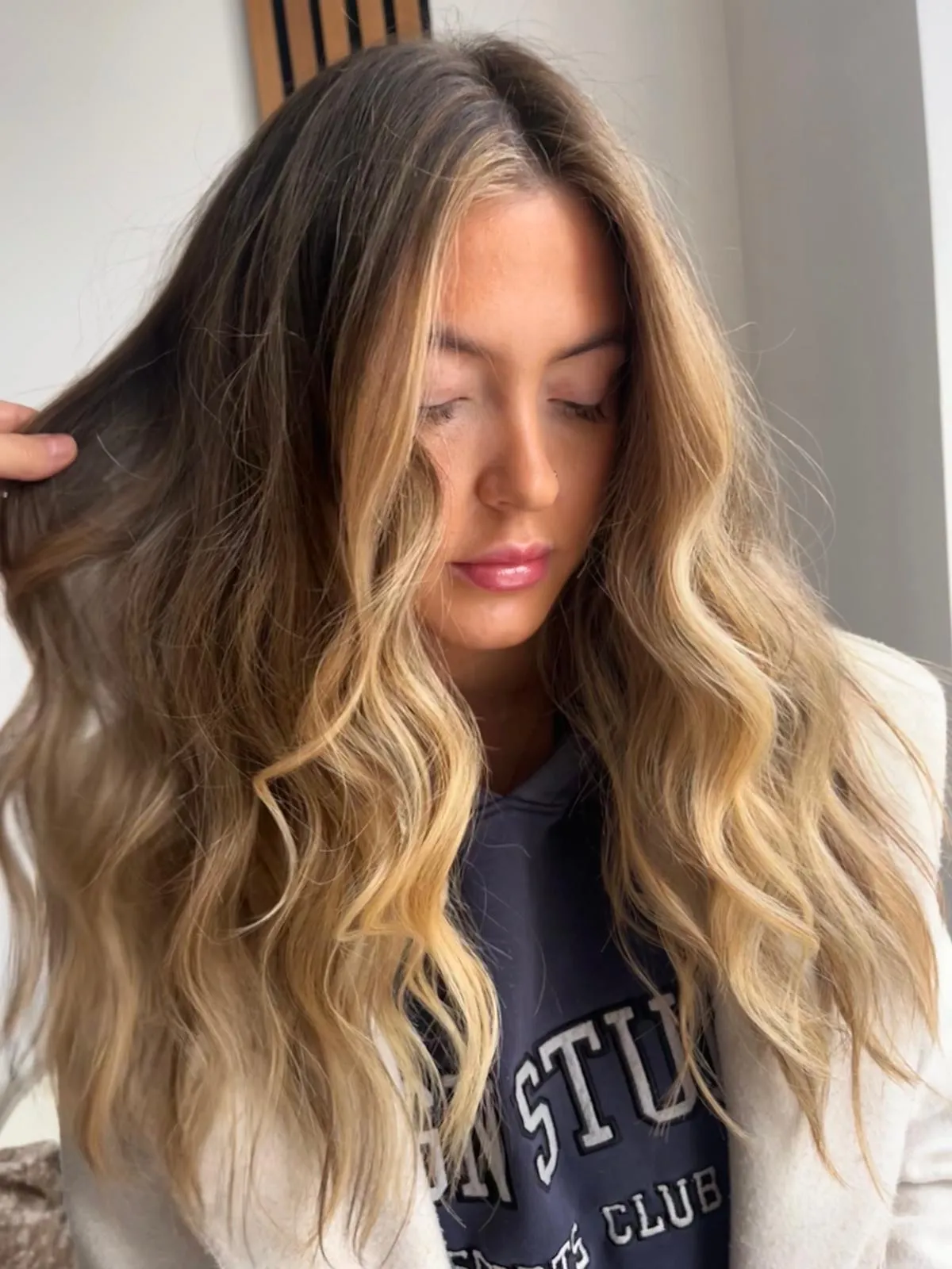 Side view after: a soft blonde balayage through brunette lengths with glossy waves and face-framing pieces.