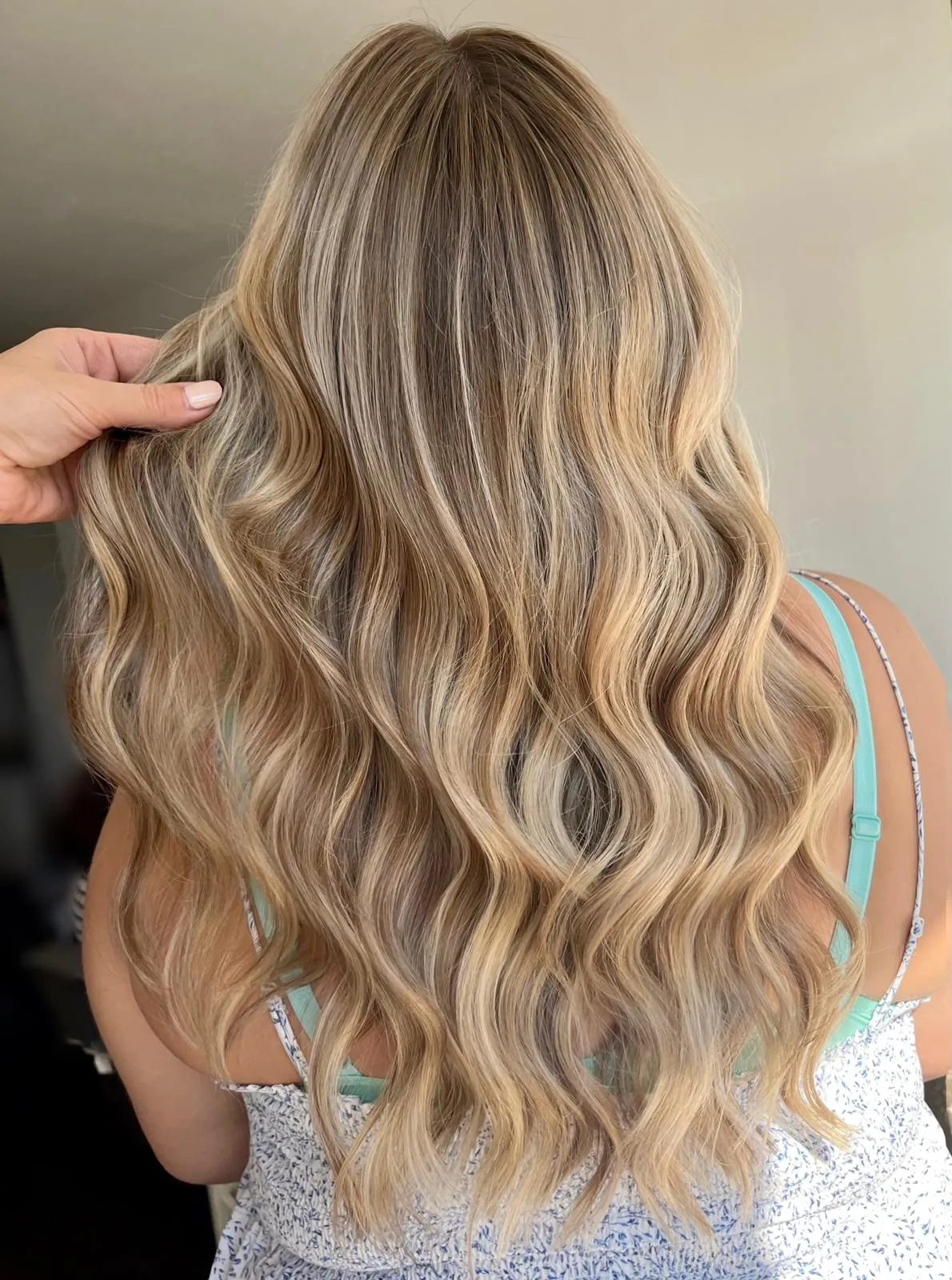 Rear view of long blonde balayage with soft waves cascading down the back.