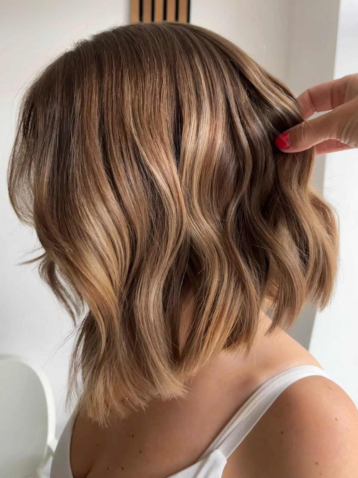 Rear view of a bronde wavy bob with golden highlights.