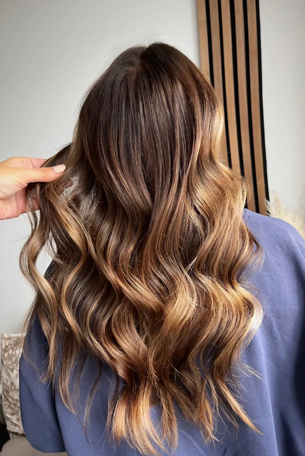Rich dark brunette with warm copper highlights, loose waves.